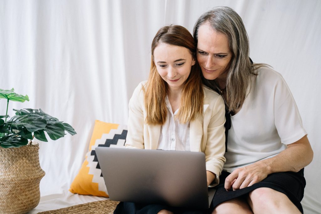 An LGBTQ neurodiverse couple is sitting behind a computer, browsing the AANE's website.